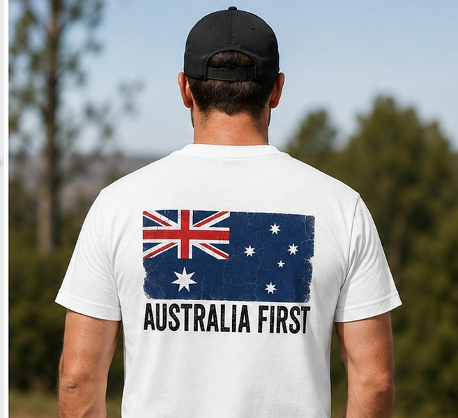 A man wearing The Australian Lobby Group white short-sleeve t-shirt and black cap, seen from behind, showing the AUSTRALIA FIRST flag graphic across the upper back.