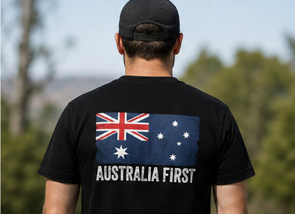 A man wearing The Australian Lobby Group black short-sleeve t-shirt and black cap, seen from behind, showing the AUSTRALIA FIRST flag graphic across the upper back.